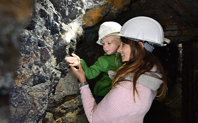 Mutter mit Kind im Bergwerksstollen Gleissinger Fels berachten Silberglitter an der Felswand.