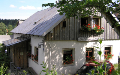 Historisches Bauernhaus des Dorfmuseums Mühlgütl in Fichtelberg mit Garten und Infotafeln.
