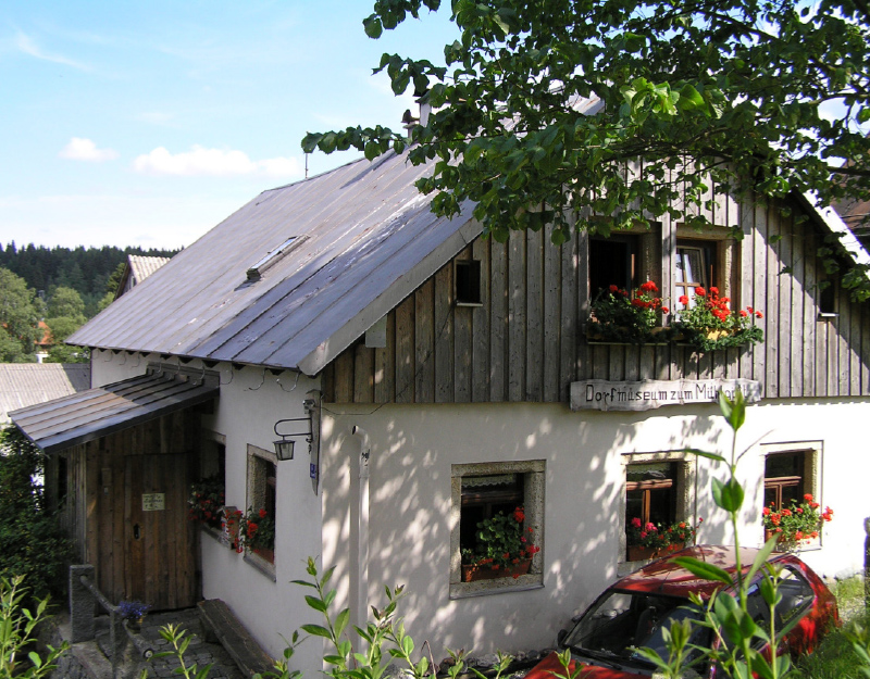 Historisches Bauernhaus des Dorfmuseums Mühlgütel in Fichtelberg mit Holzfassade und Blumenschmuck.