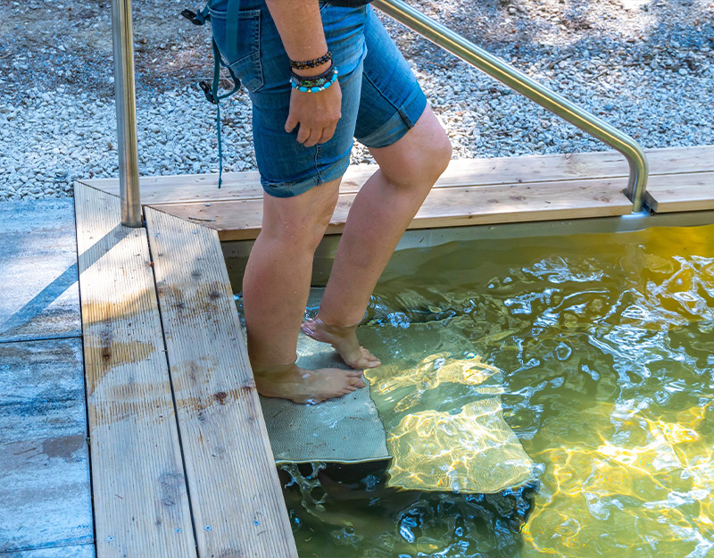 Frau beim Einstieg in das Kneippbecken im Mausbachtal Warmensteinach in ruhiger Waldlage.