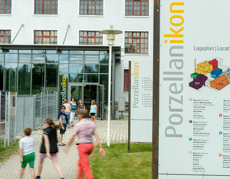 Eingangsbereich des Porzellanikon Museums mit Besuchern und Lageplan.