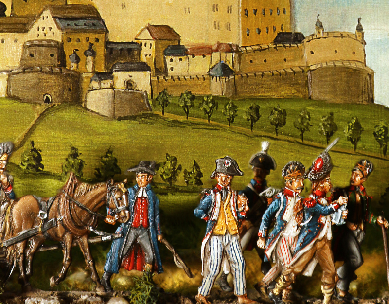 Detailaufnahme historischer Zinnfiguren mit Soldaten und Pferd vor einer gemalten Stadtansicht im Zinnfigurenmuseum Kulmbach.