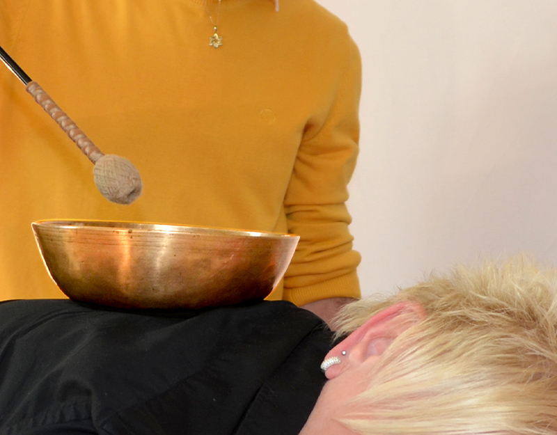 Klangschalen-Anwendung auf dem Rücken einer liegenden Person.