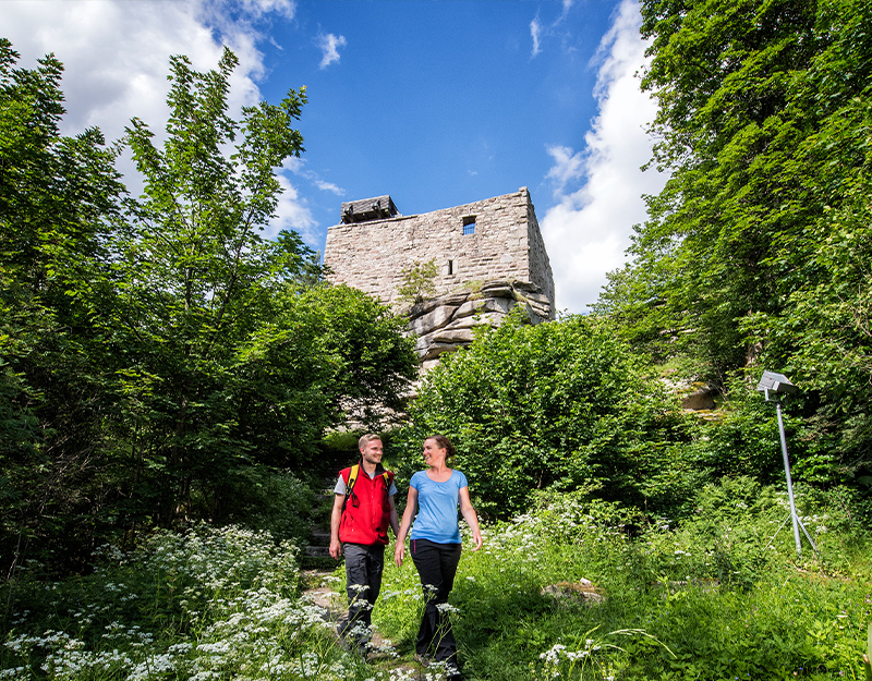 Wanderer vor der Burgruine Epprechtstein bei Kirchenlamitz auf einem Waldpfad.