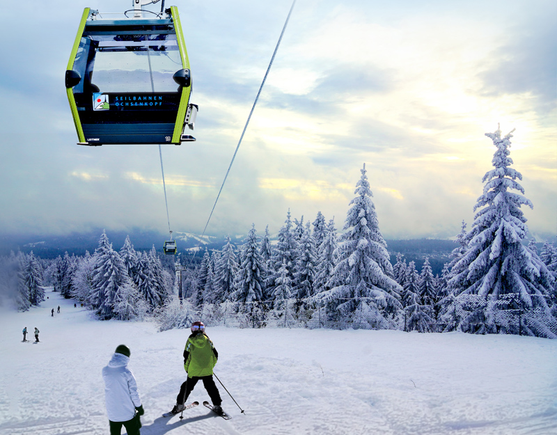 Seilbahn Ochsenkopf Süd im Winter mit verschneiten Bäumen. Darunter fahren Skifahrer die Piste Richtung Warmensteinach hinunter.