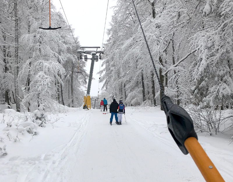 Skifahrer lassen sich mit dem Schlepplift den Kornberg bei Selb im verschneiten Winterwald hinausziehen.
