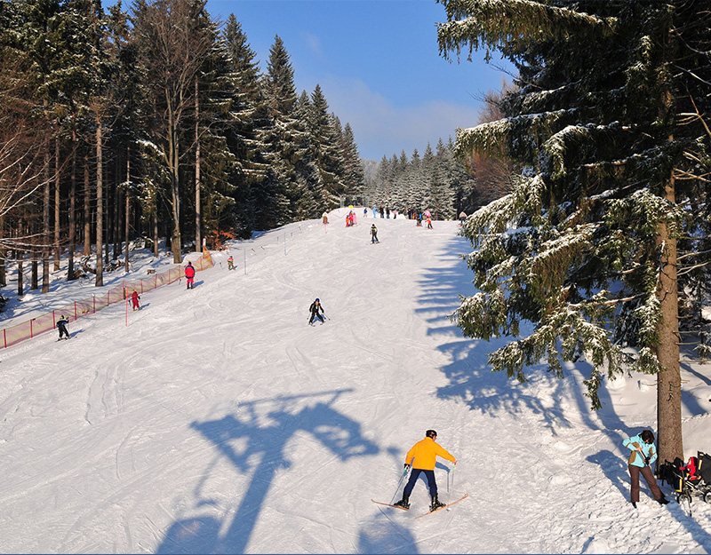 Anfänger-Skilift mit Skifahrern auf leichter Übungspiste im Schnee.