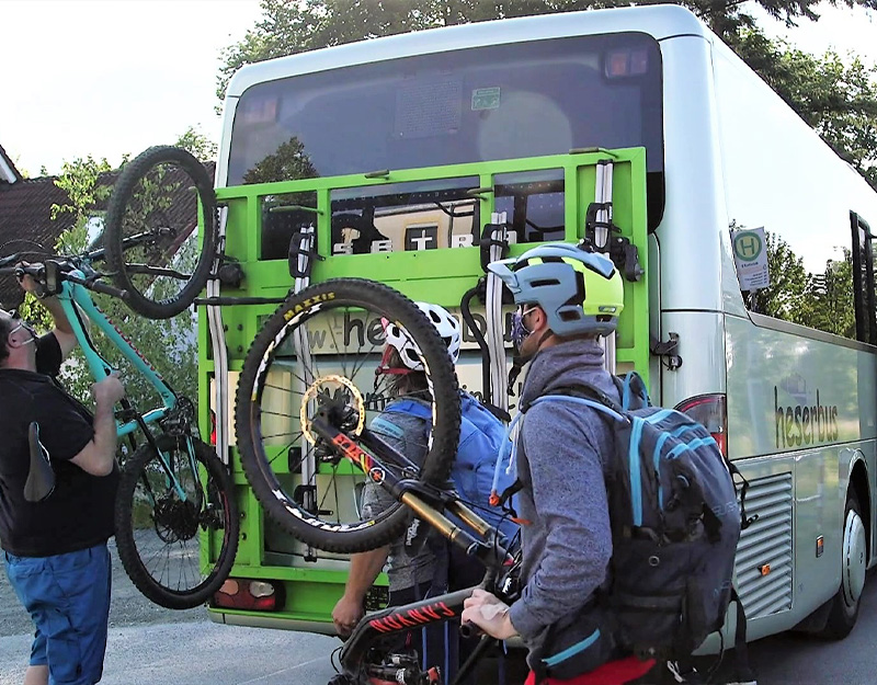 Radfahrer laden Mountainbikes auf einen Bus mit Fahrradträger im Fichtelgebirge.