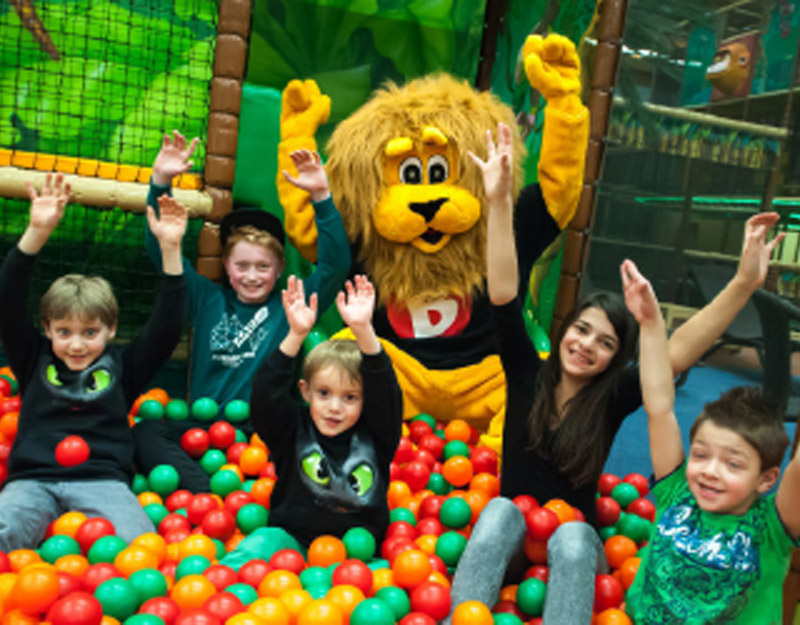 Kinder spielen im Indoor-Freizeitpark mit Maskottchen im Bällebad