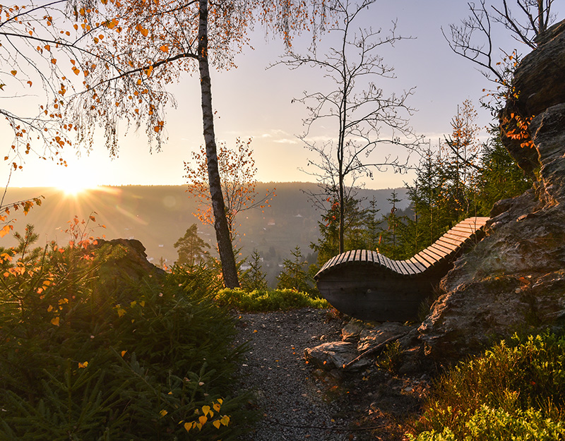 Sonnenuntergang am Wellnesswanderweg mit Holzliege und Talblick