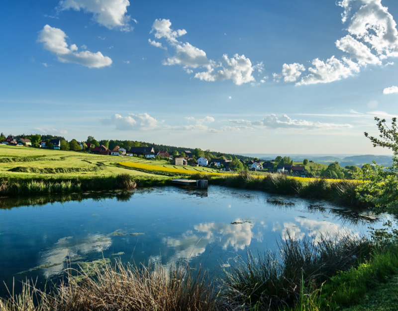 Dorfansicht von Wülfersreuth, einen Ortsteil von Bischofsgrün, an der Markgrafenrunde mit Weiher und Landschaft.