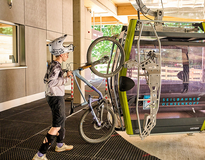 Radfahrer befestigt sein Mountainbike an einer modernen Gondel der Seilbahn Ochsenkopf.